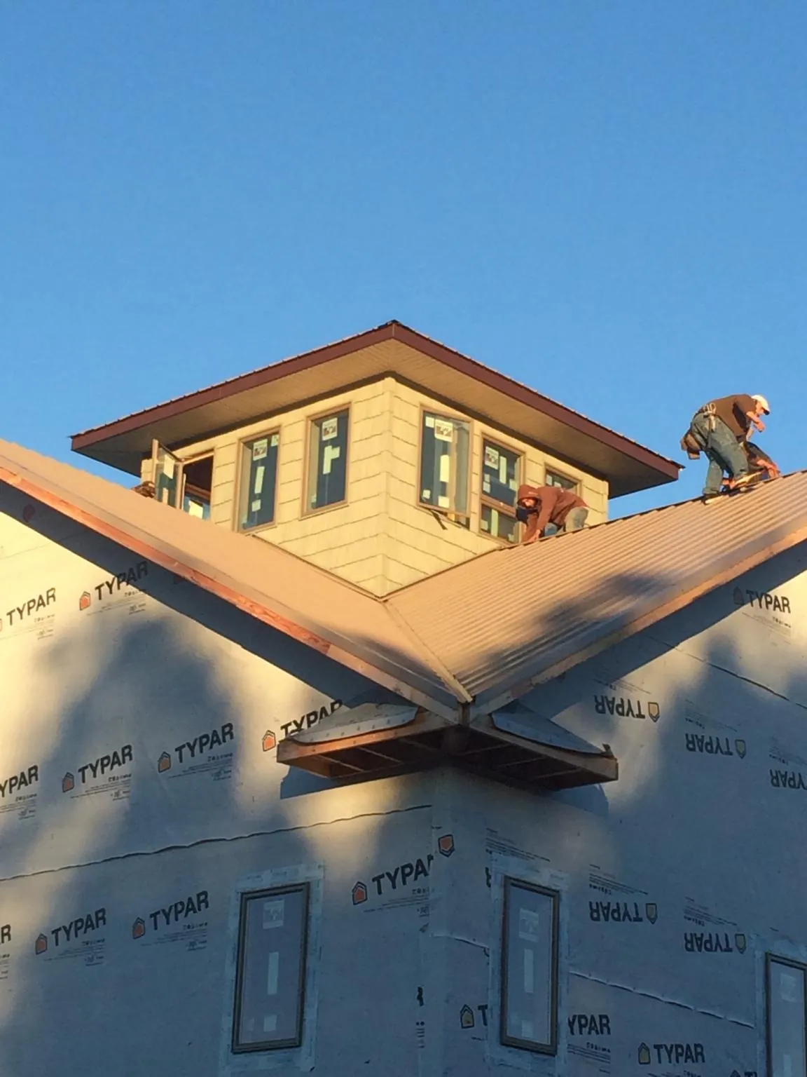 Roofers working around a rooftop cupola on a new metal roof at sunset — Roof Waterproofing in Industry by Roofing Brothers